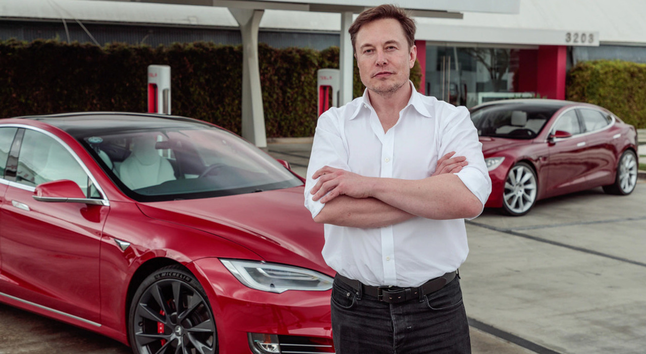 Elon Musk, numero uno del marchio americano di auto elettriche, con due Tesla alle sue spalle